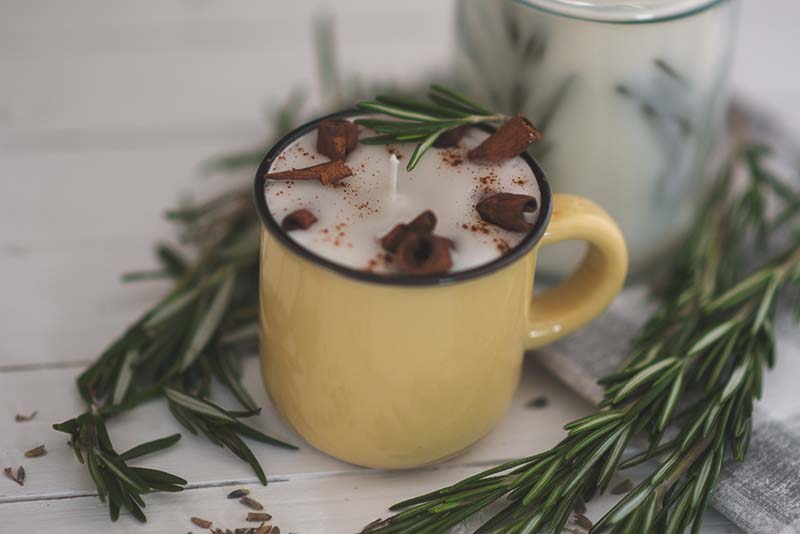 rosemary cinnamon herbal candle in a yellow mug